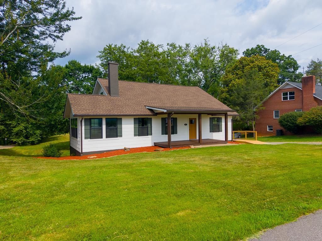 Front and side of the house from the lawn, with the brick chimney and the ramp to the side entry
