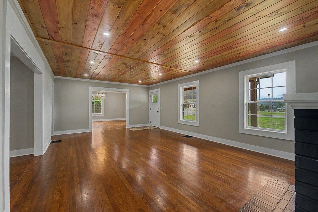 Empty living room with restored hardwood floors, a tongue-and-groove wood ceiling, and recessed lights