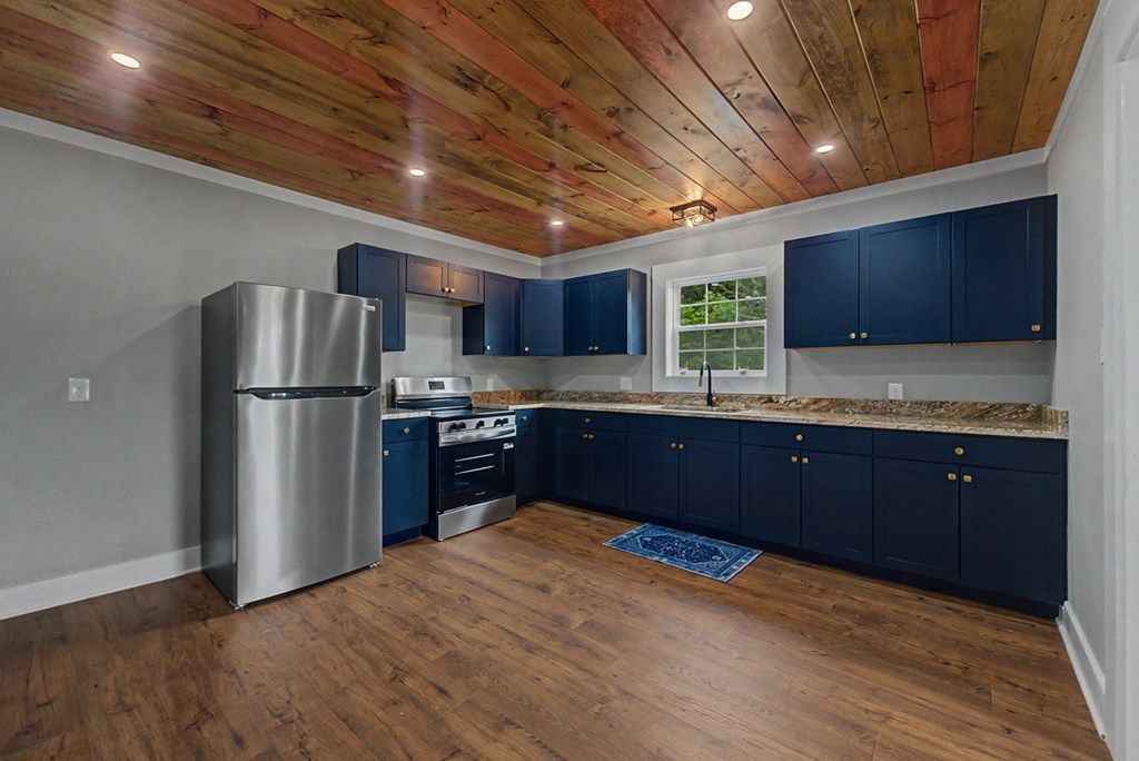 Kitchen with navy shaker cabinets, countertops, a stainless refrigerator and range, and a window over the sink