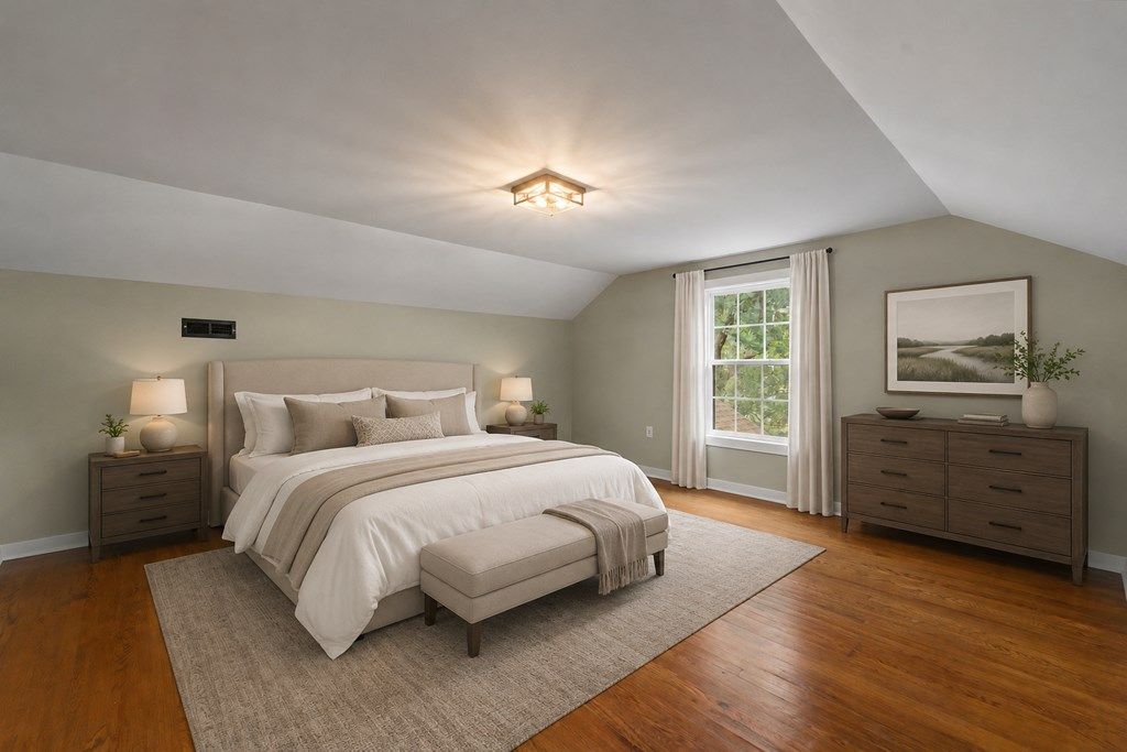 Bedroom with a sloped ceiling and hardwood floors, shown with a virtual bed and dresser