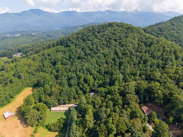 Aerial view over the wooded hills toward the mountains