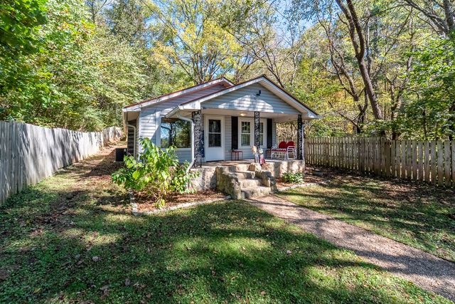 Cottage and front yard from the side, inside the wood fence
