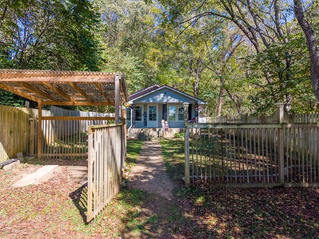 Pergola-covered gate into the front yard, with the cottage beyond