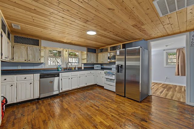Kitchen with white cabinets, stainless appliances and a wood ceiling